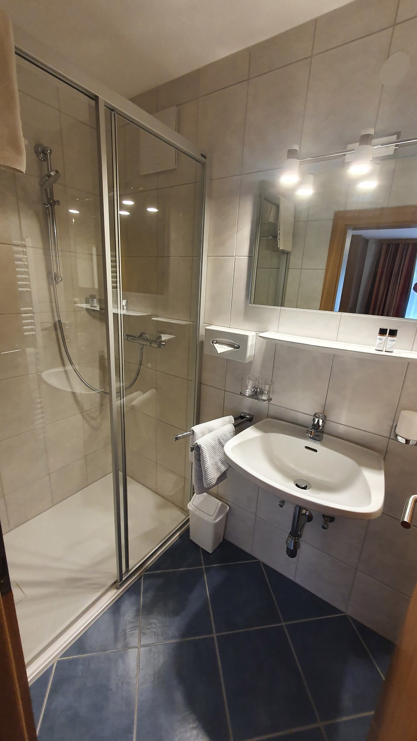 Badezimmer mit Dusche und Waschbecken im Hotel Dorfblick