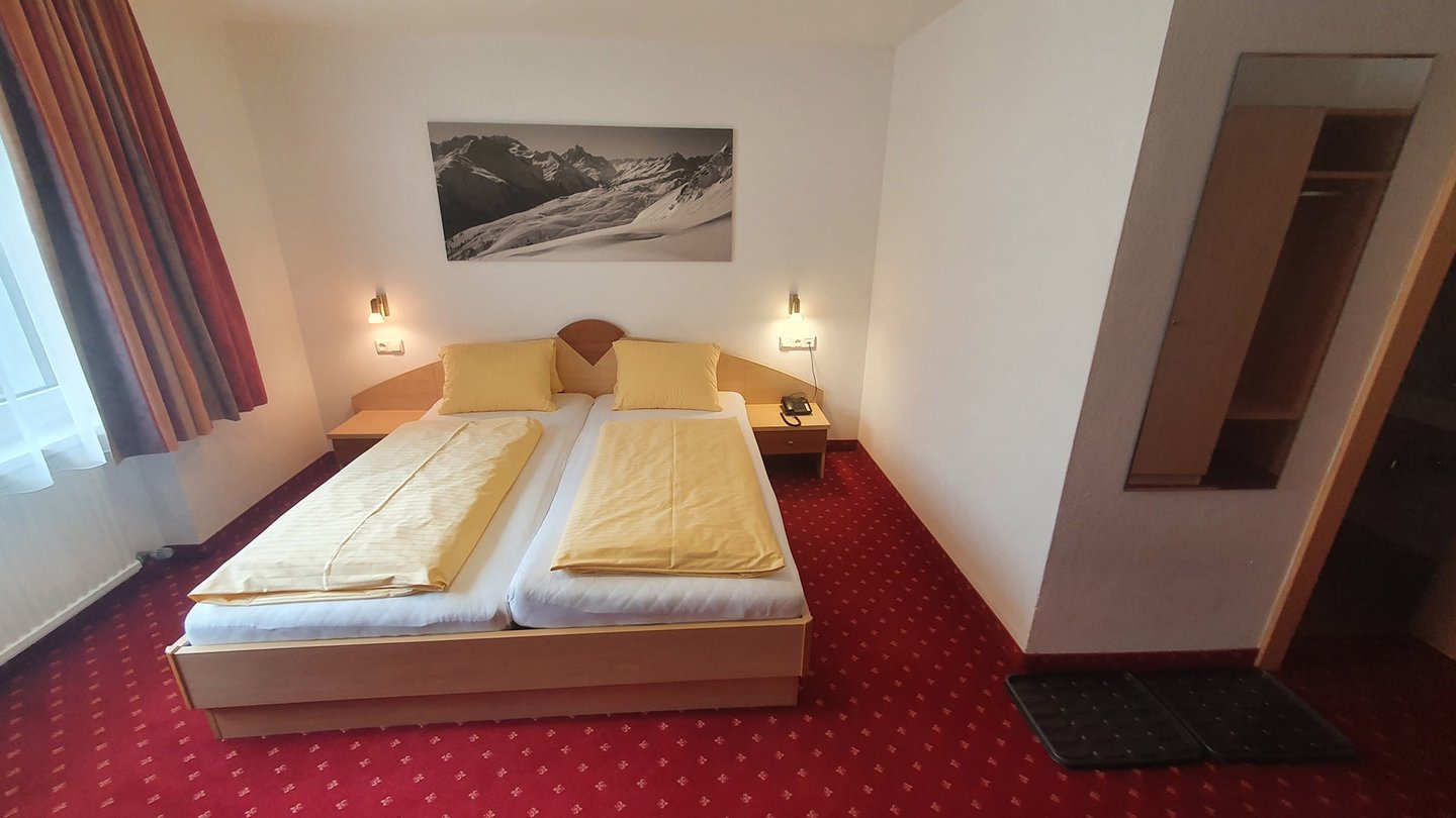 Doppelzimmer mit Doppelbett und Kleiderschrank im Hotel Dorfblick