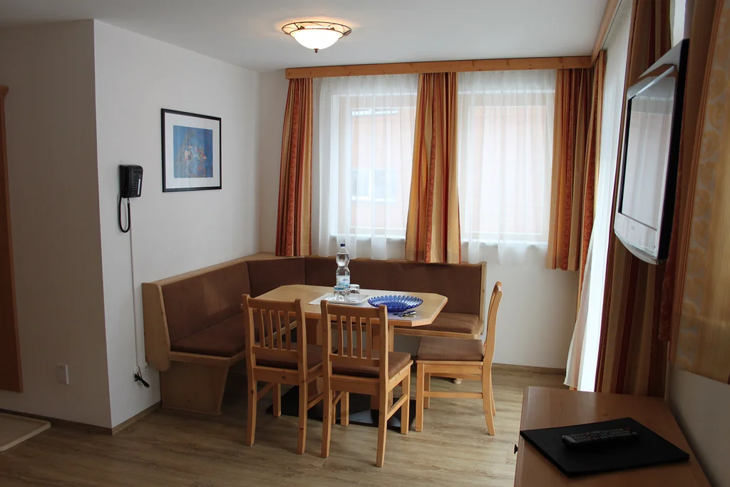 Appartement 11: Wohnraum mit Eckbank, Esstisch und Fernseher