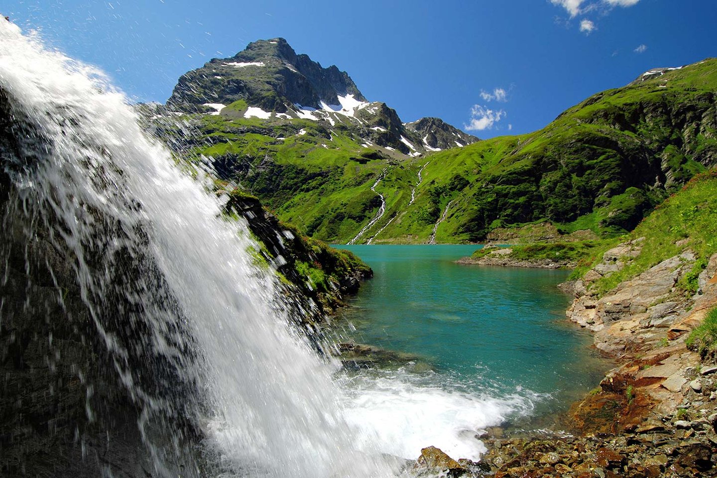 Wasserfall an einem türkisen Bergsee am Arlberg
