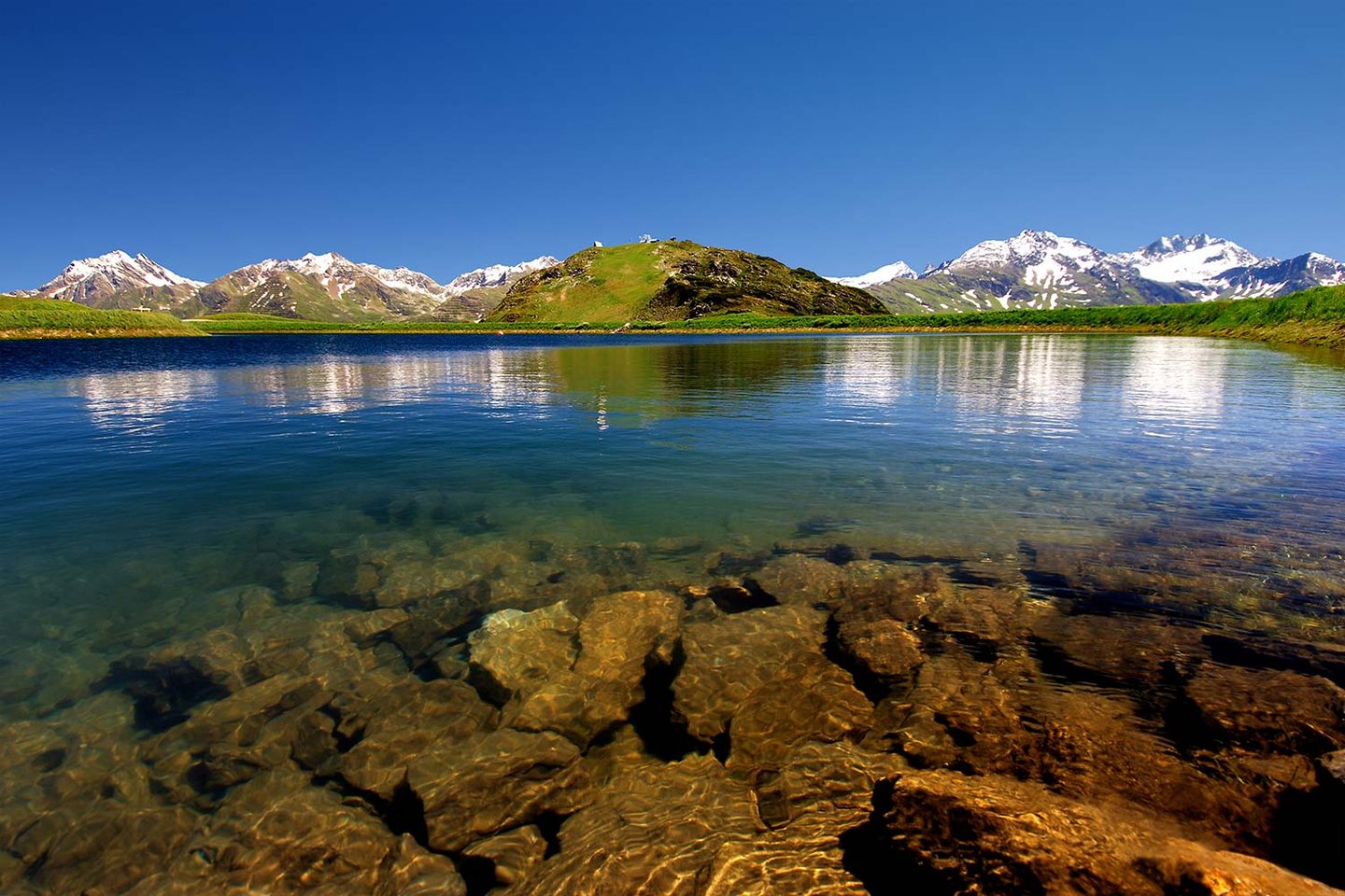 Klarer Bergsee mit Blick auf die Arlberger Gipfel