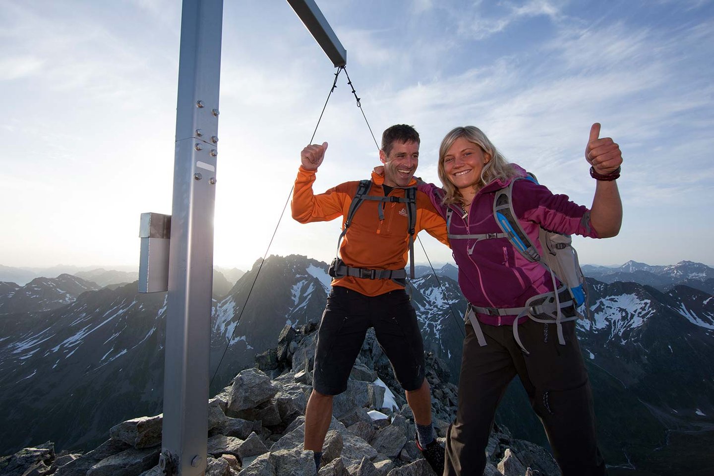 Zwei Wanderer freuen sich am Gipfelkreuz am Arlberg